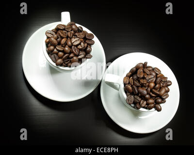 Draufsicht auf zwei Tassen gefüllt mit ganzen gerösteten Kaffeebohnen. Stockfoto