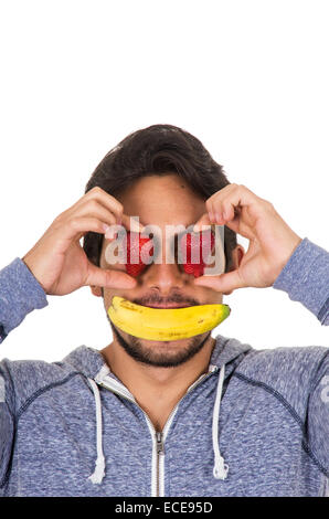 Closeup Portrait junge lustige Manndeckung Gesicht mit roten Erdbeeren und Bananen Stockfoto