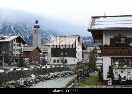 Alphütten und der Turm der St.-Nikolaus-Kirche in Lech, Österreich. Stockfoto