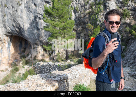 Mann unter Bild mit Handy in Bergen, Tarragona, Katalonien, Spanien Stockfoto