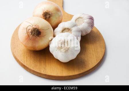 Zwiebeln und Knoblauch auf ein Schneidebrett auf weiß Stockfoto