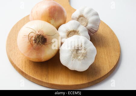 Zwiebeln und Knoblauch auf ein Schneidebrett auf weiß Stockfoto