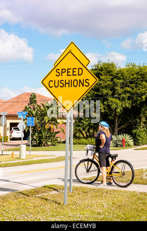 Frau Radfahrer beschlossen, den Bürgersteig zu verwenden, anstatt überqueren die Geschwindigkeit Kissen vor ihr, wie die Zeichen voraussagt. Stockfoto