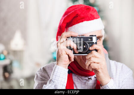 Ältere Mann auf Santas Hut nehmen Foto auf Weihnachten Hintergrund Stockfoto