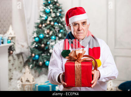 Senior Mann mit einer roten Geschenkbox auf Weihnachten Hintergrund Stockfoto