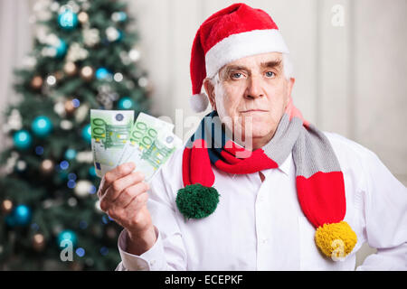 Senior woman in Nikolausmütze Weihnachten Hintergrund Geld festhalten Stockfoto