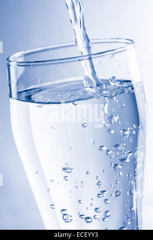 Gießen Wasser in Glas in blauen Tönen Stockfoto