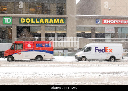 Toronto, Kanada. 11. Dezember 2014. Ersten großen Schneesturm Torontos kaufte in der Nähe von 20 cm Schnee in die Stadt.  Ein Canada Post-Lieferwagen und ein FedEx Lieferwagen geparkt auf einem schneebedeckten Teil der Sheppard Avenue in North York. Bildnachweis: EXImages/Alamy Live-Nachrichten Stockfoto