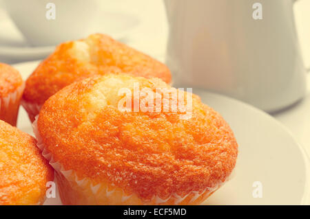 eine Platte mit einigen Magdalenas, typisch spanische schlicht Muffins und eine Tasse Kaffee im Hintergrund auf einem gedeckten Tisch Stockfoto