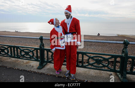 Hove, Brighton, Sussex, UK. 13. Dezember 2014.  Ein paar nehmen Sie Teil an der jährlichen Santa Dash an Hove Küste heute Morgen eine Reihe von Nächstenliebe Santa Dash läuft während der festlichen Jahreszeit in Großbritannien jährlich statt. Bildnachweis: Simon Dack/Alamy Live-Nachrichten Stockfoto