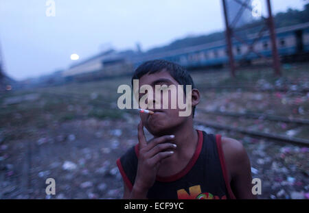 Rana Alter 12 ist eine Obdachlose Straßenhändler qualmender Zigarette in Kamalapur Bahnhof in Dhaka. Städte in Bangladesch sind mit dichten Slums, Squattersiedlungen und Pflaster Wohnungen, jedes Haus, Tausende von Kindern überfüllt. Zunehmende Armut im ländlichen Raum und entsprechenden Landflucht weiterhin die Zahl der Menschen, die in städtischen Slums und auf den Straßen anschwellen. Probleme der Arbeitslosigkeit im ländlichen Raum, Landlosigkeit, Flusserosion, Naturkatastrophe, Familienkonflikte und schwachen Gesetz und Ordnung Ursache ländlichen Familien zum Verlassen ihrer Heimat auf der Suche nach besseren Aussichten in den urbanen Zentren. Diese Bewegung Stockfoto