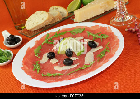 Carpaccio mit Limetten, Oliven, Rucola und Parmesan Stockfoto