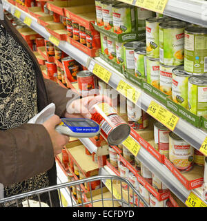 Tesco Supermarkt Shopper mit handheld Scan, während Sie kaufen Gerät Einkäufe auf digitale Anzeige für den Download auf bis London England UK aufzeichnen Stockfoto