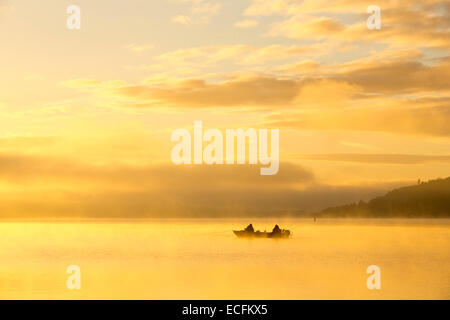 Sonnenaufgang über Männer Angeln in einem Boot auf dem Lake Windermere in Ambleside, Lake District, Großbritannien. Stockfoto