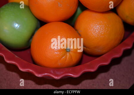 Orangen in Schüssel und Apfel Stockfoto