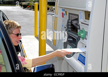 Reife kaukasischen Frau in einem Auto mit einem Laufwerk bis ATM-Maschine. Stockfoto