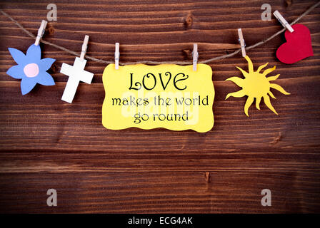 Gelb-Tag oder Label mit Herz und Blume und Cross und Sonne auf einer Linie mit Leben Zitat Love Makes The World Go Round auf hölzernen Ba Stockfoto