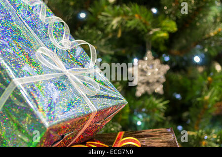 Glänzend leuchtende Geschenke unter dem geschmückten grünen Weihnachtsbaum Stockfoto