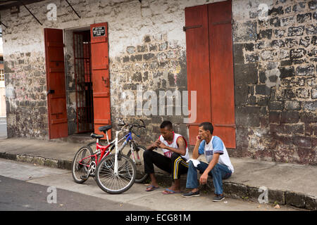 Mauritius, Mahebourg, Stadtmitte, Männer mit Fahrrädern setzte sich auf den Bürgersteig vor der Kolonialzeit shop Stockfoto