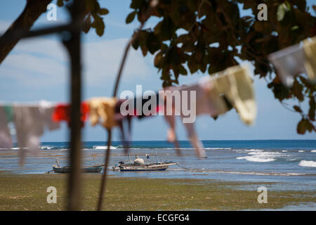 Fischerboote und sonnentrocknende Kleidung am Strand von Tanjung Setia in Krui, an der Westküste von Lampung, Indonesien. Stockfoto