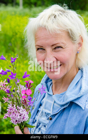 Porträt einer Frau mittleren Alters mit einem Bouquet von wilden Blumen Stockfoto