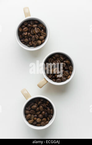 Kaffeebohnen in Tassen über weißen Tisch, über Ansicht Stockfoto