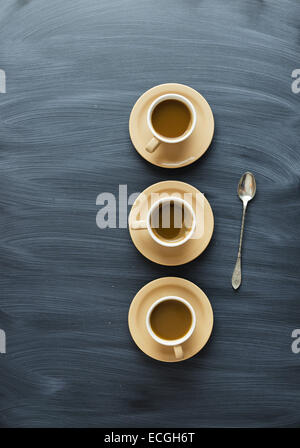 Kaffeetassen und einen Löffel über Kreide strukturierte Tisch, über Ansicht Stockfoto