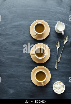 Kaffee Tassen, Löffel und Milch jar über Kreide strukturierte Tisch, über Ansicht Stockfoto