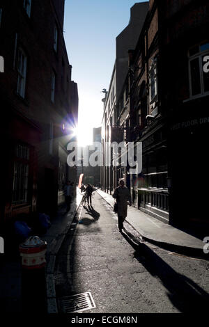 Fußgänger, Sonnenschein und Schatten in der Ecke des Sandys Zeile & Widegate Street Spitalfields London, UK KATHY DEWITT Stockfoto
