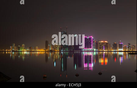 Nacht Skyline der modernen Stadt mit leuchtenden Lichter und Spiegelungen im Wasser. Manama, der Hauptstadt des Königreichs Bahrain, Naher Osten Stockfoto