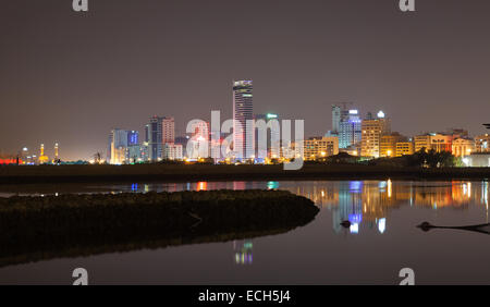 Nacht Skyline der Stadt, glänzende Lichter und Spiegelungen im Wasser. Manama, der Hauptstadt des Königreichs Bahrain, Naher Osten Stockfoto
