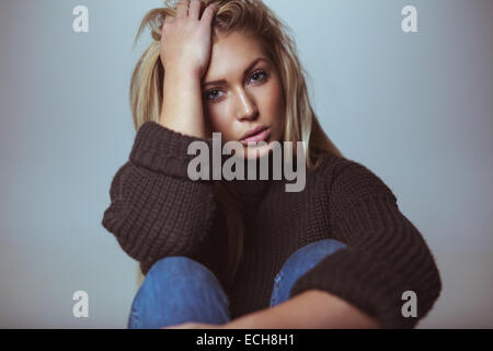 Bild der schönen weiblichen Modell tragen Pullover mit der Hand im Haar. Studioaufnahme von attraktiven Frau. Stockfoto