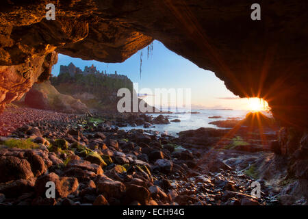 Höhle Sonnenuntergang Bilder Dunluce Castle, Causeway-Küste, County Antrim, Nordirland. Stockfoto