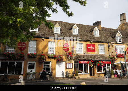 Eine Reihe von Cotswold Townhäuser und Geschäfte mit dem alten Bestände Hotel. Stockfoto