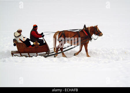 Italien, Cortina d ' Ampezzo: Paar in der Weihnachtszeit auf Schlitten Pferd über den zugefrorenen See sitzen unter Decken im Winter auf Schnee Stockfoto