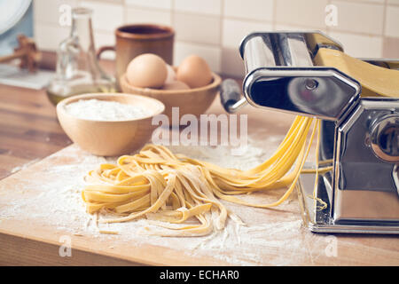 frische Nudeln und Pasta-Maschine am Küchentisch Stockfoto