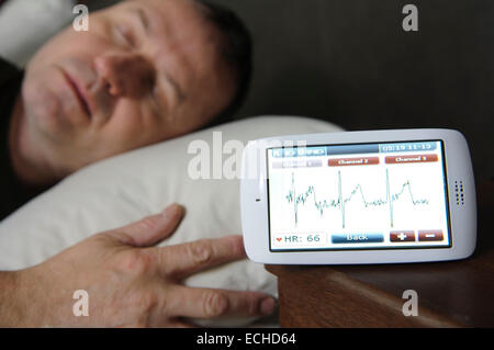 Mann schläft während seiner ECG mit einem Custo Kybe Pulsmesser überwacht. Stockfoto