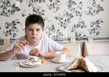 Junge trinkt Tee mit Kuchen am Tisch Stockfoto