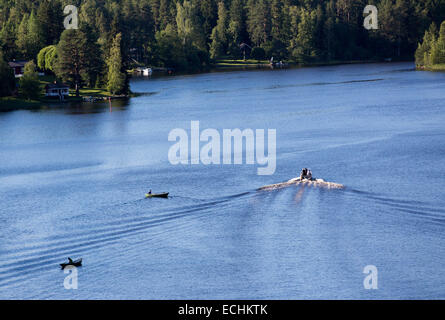 Luftaufnahme eines Motorbootes, das zwei Fischer auf Ruderbooten / Skiffs / Beiboot / Schlauchboote passiert, Finnland Stockfoto