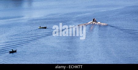 Luftaufnahme eines Motorbootes, das zwei Fischer auf Ruderbooten / Skiffs / Beiboot / Schlauchboote passiert, Finnland Stockfoto
