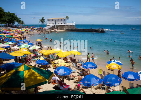 SALVADOR, Brasilien - 13. Oktober 2013: Beachgoers versammeln sich unter bunten Sonnenschirmen am hellen Nachmittag am Porto da Barra. Stockfoto