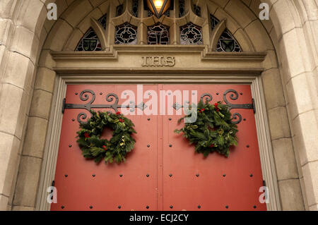 Traditionelle grüne und rote Weihnachtskranz hängen an der Tür des kanadischen Memorial United Church, Vancouver, BC, Kanada Stockfoto