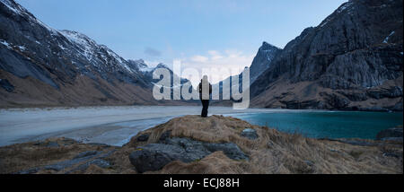 Weibliche Wanderer nimmt im Hinblick auf die malerische Berglandschaft am Horseid Strand, Moskenesøy, Lofoten Inseln, Norwegen Stockfoto