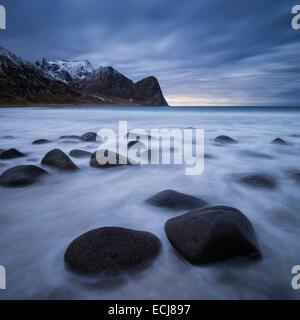 Wellen fließen unter Felsbrocken am malerischen Unstad Strand, Leknes, Lofoten Inseln, Norwegen Stockfoto