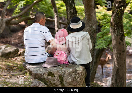 Ein Familienpicknick im Schatten im Nara Park, Nara, Japan, wo heilige Sika-Hirsche frei herumstreifen und oft von Besuchern betteln Stockfoto