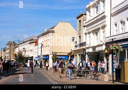 Geschäfte mit Kunden und Touristen entlang der High Street, Cheltenham, Gloucestershire, England, UK, Westeuropa. Stockfoto