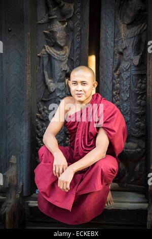 Myanmar (Burma), Mandalay-Division, Innwa Bagaya Kyaung, burmesischen Mönch sitzt vor Teak Holztür Stockfoto