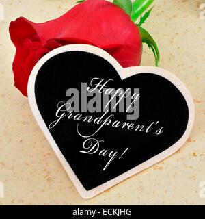 Satz frohen Tag der Großeltern mit Kreide auf einer Tafel Herzform mit einer roten Rose im Hintergrund geschrieben Stockfoto