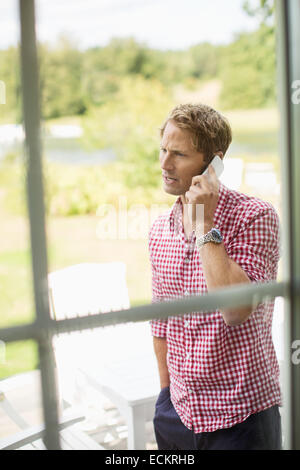 Mann mit Handy auf Veranda Stockfoto