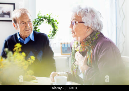 Ältere Frau im Gespräch mit Freunden am Frühstückstisch im Pflegeheim Stockfoto